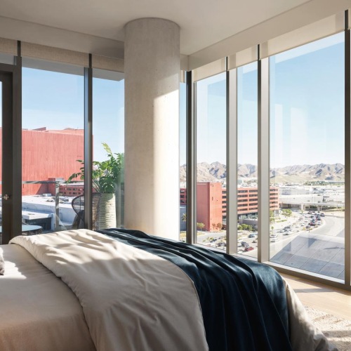 a room with a large window and a bed with a view of the city